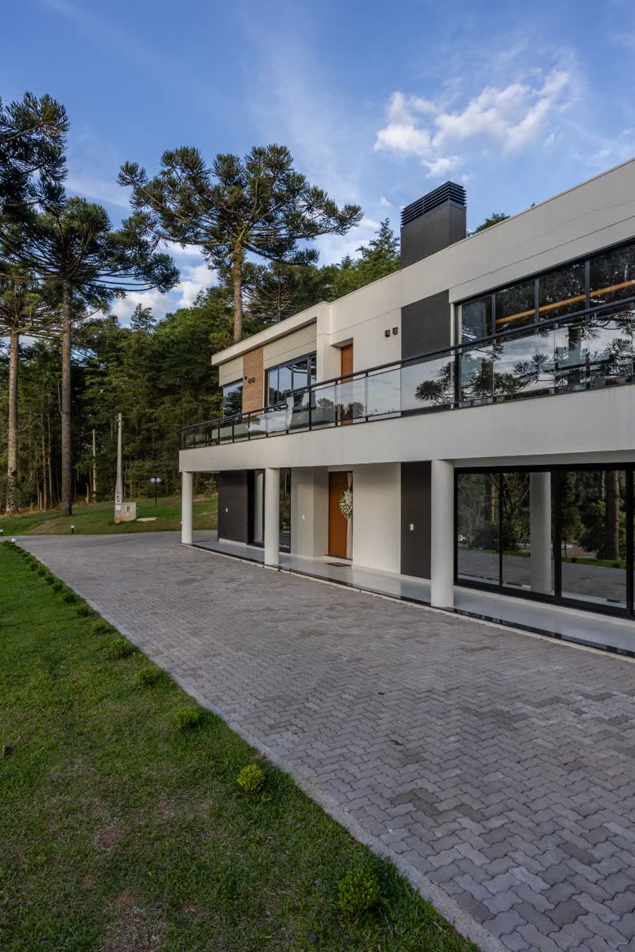 Detalhe da residência entre araucárias ao entardecer